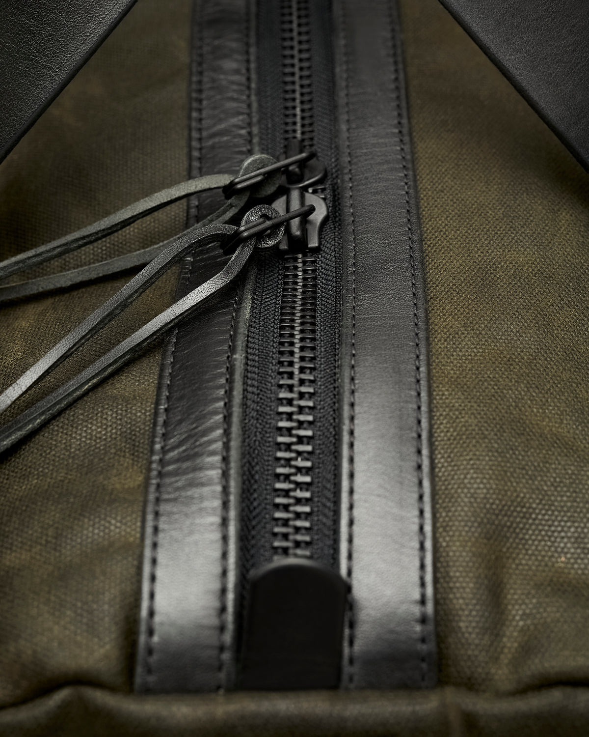 Close-up of hand-polished and waxed leather edges and brass zippers on Kvåle duffel bag