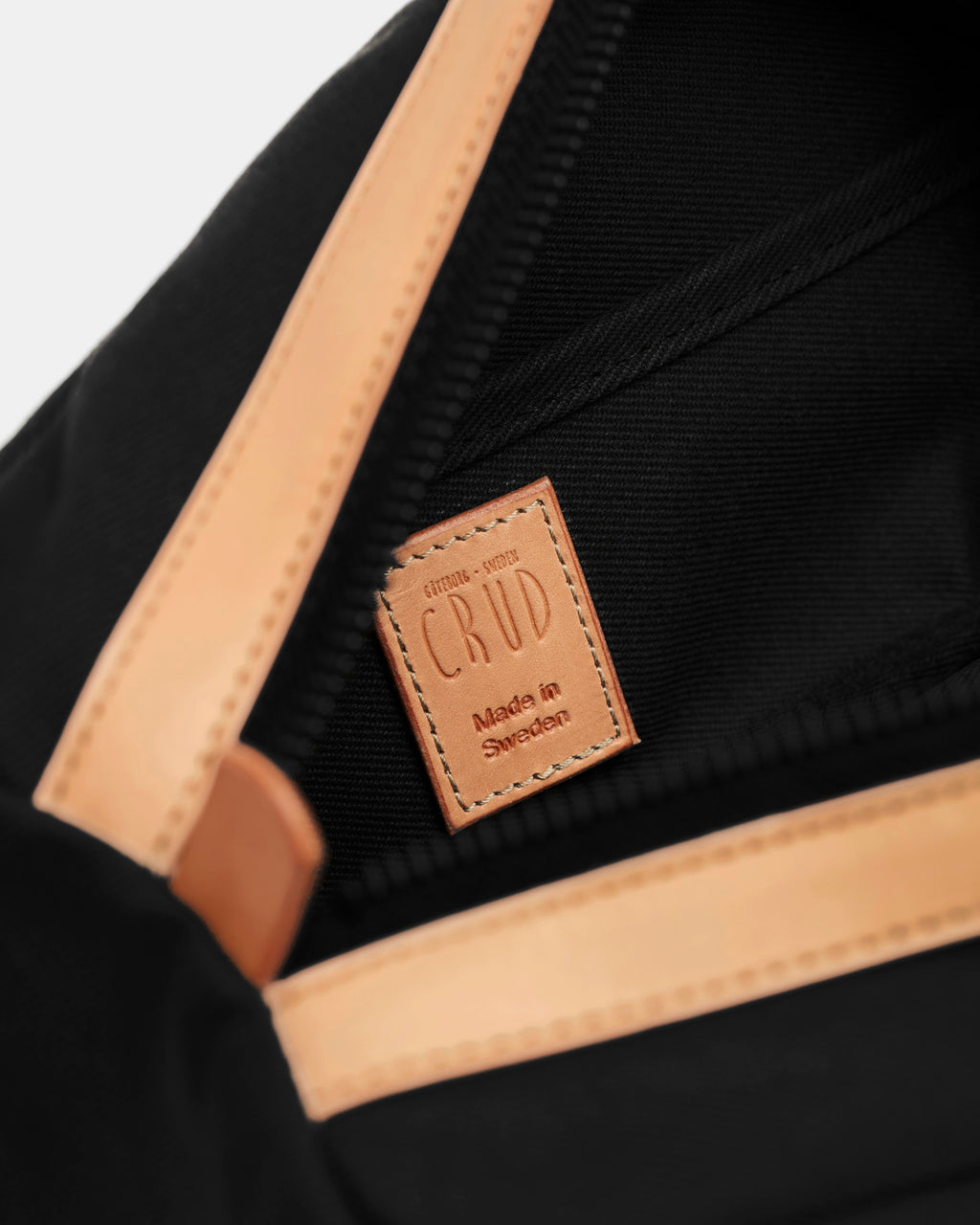 Inside of black toiletry bag with leather label stamped Crud Made in Sweden