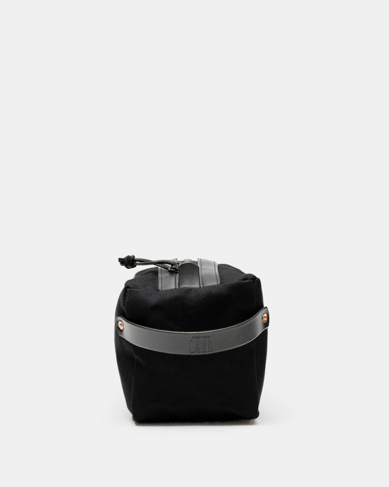 End view of black Crud toiletry bag with embossed black leather strap