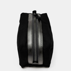 Top view of black toiletry bag with zipper and black leather trim
