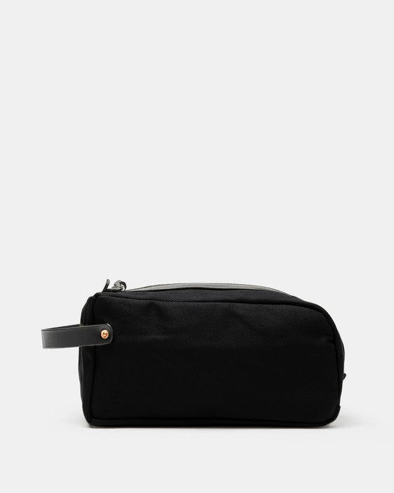 All-black waxed canvas toiletry bag with black leather handle by Crud