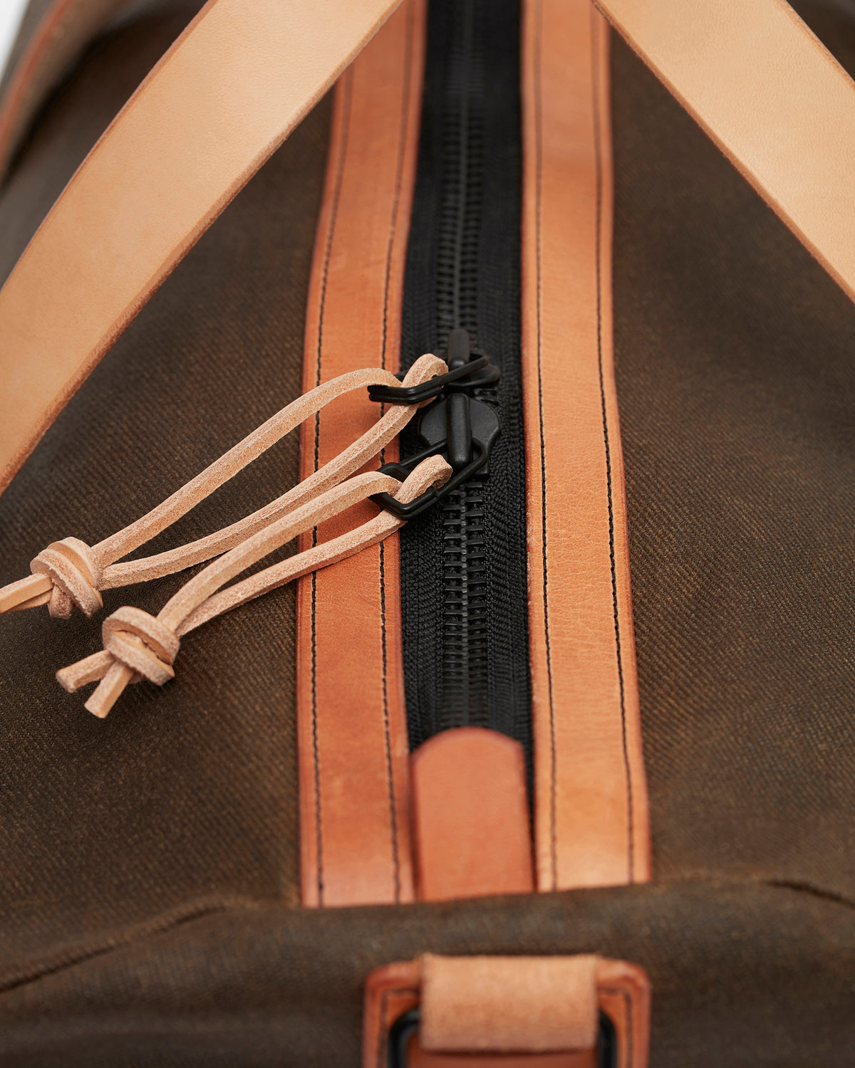 Close-up of matte black YKK brass zipper on Kvåle waxed canvas duffle